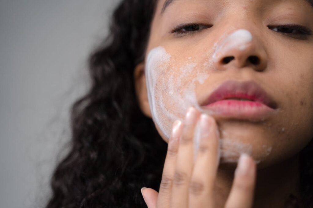 A woman applying skincare cream on her face, focusing on self-care and beauty routines.